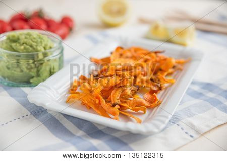 Healthy organic carrot vegetable chips with guacamole dip