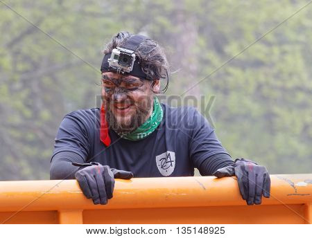 STOCKHOLM SWEDEN - MAY 14 2016: Smling man with mud in his face climbing a orage container obstacle in the obstacle race Tough Viking Event in Sweden May 14 2016