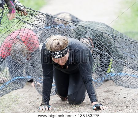 STOCKHOLM SWEDEN - MAY 14 2016: Group of women crawl under a net obstacle in the obstacle race Tough Viking Event in Sweden May 14 2016
