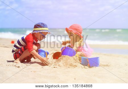 kids play with sand on summer beach, family vacation