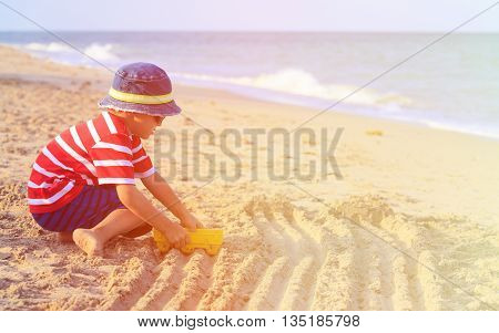 little boy play with sand on summer beach