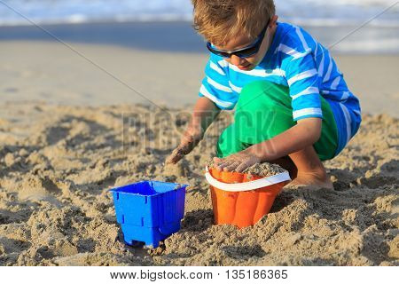 little boy play with sand on summer beach