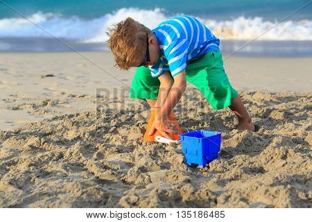 little boy play with sand on summer beach
