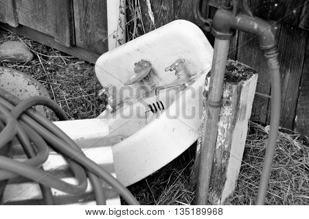 An old sink and other junk sitting out by a barn.