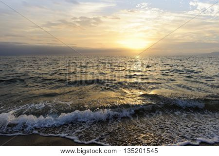 Ocean sunset is a brightly lit golden seascape with a gentle wave rolling to the shore.