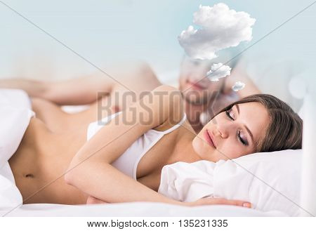 Woman with thoughts cloud sleeping in bed with her boyfriend
