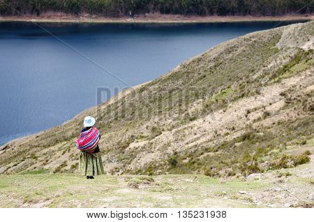 South America Bolivia - Isla del Sol on the Titicaca lake the largest highaltitude lake in the world. Woman standing in the traditional dress on the lake Titicaca