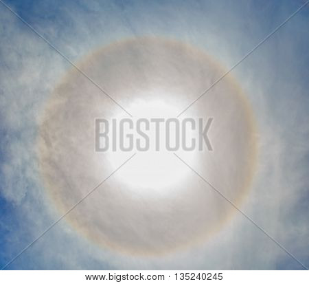 Circles halo in blue cloudy sky around of the sun