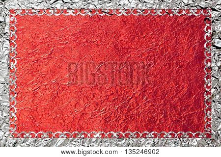 Shiny silver frame with a pattern on the red foil background.