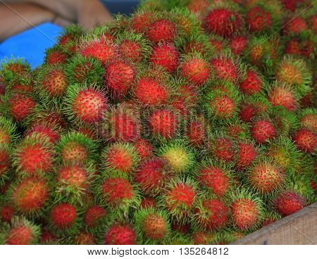 Pile of fuzzy red rambutan fruit for sale, Ranot waterside market, Thailand