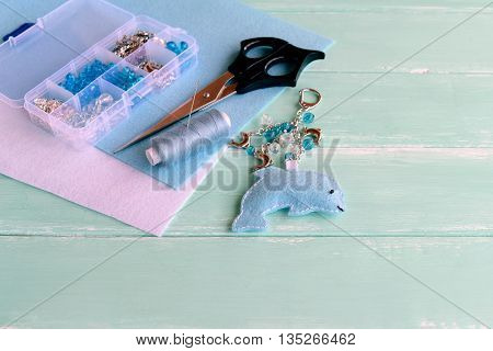 Felt dolphin keyring in blue. Ocean keychain charm. Key chain handcrafted, summer accessory. Plastic box with beads and metal parts, scissors, thread, needle, felt pieces