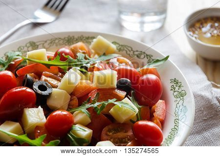 Close up of a plate of vegetable salad with a fork and a glass of water