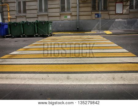 white and yellow lines pedestrian crossing on asphalt and green garbarge dumpsters on street of Moscow Russia