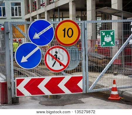group of road traffic signs on the metal gate of the construction site