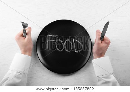 Man holding fork and knife with empty plate. Hunger concept