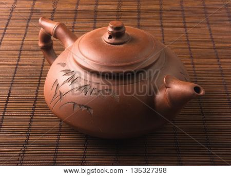 brown Chinese teapot of Yixing clay with traditional ornament on bamboo Mat