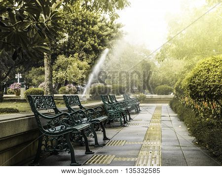 bench in the park with water sprinker and morning light