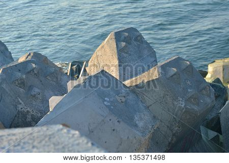 Close Up Of Breakwater Made Of Concrete Tetrapods In The Sunset, With The Calm Sea In Background. Se