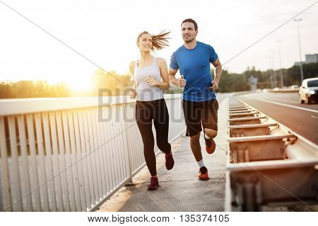 Active young couple jogging outdoors during sunset