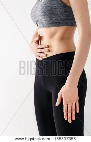 Sporty beautiful young woman practicing Uddiyana Bandha technique on the white background
