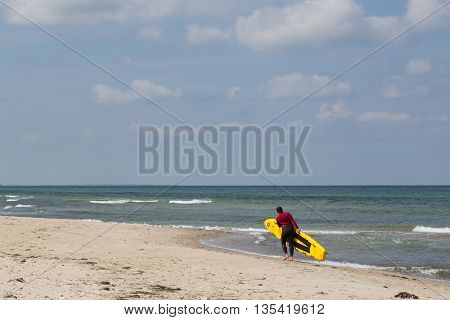 Tisvilde, Denmark - June 20, 2016: A female Lifeguard with her surf board at Tisvilde beach.