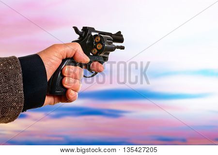 detail of hand with a handgun at sunset