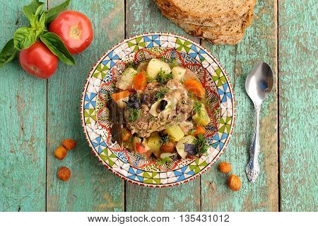 Homemade chorba soup with lamb meat on bone potato carrots bay leaf and dried apricots served with basil and tomatoes overhead view