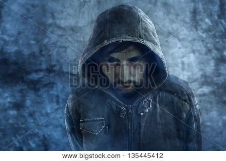 Spooky ghost appearance of dead male person with black eyes and hooded jacket