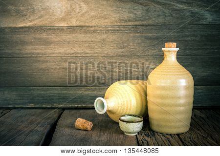 Still life of sake bottles with light on wood background.