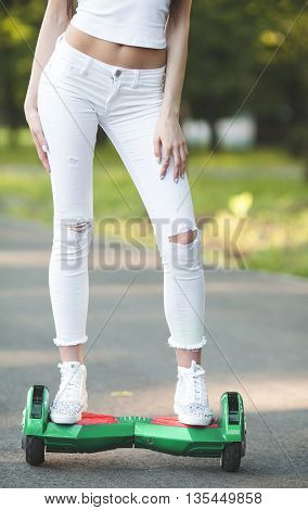 Girl using a self-balancing two-wheeled board. The gyroscope based dual wheel electric scooter is also called a smart balance wheel. Feet on hover board scooter