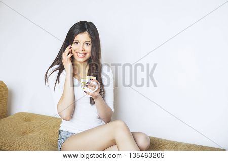 beautiful young woman is using an app in phone device to send a text message . Portrait of beautiful young woman using her mobile phone at home.