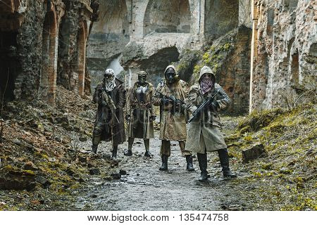 Nuclear post-apocalypse. Survivors in tatters and gas mask on the ruins of the destroyed city