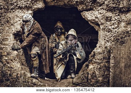 Nuclear post-apocalypse. Survivors in tatters and gas mask on the ruins of the destroyed city