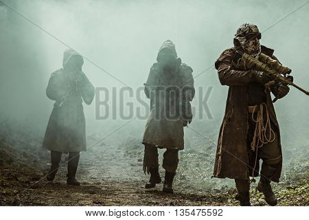 Nuclear post-apocalypse. Survivors in tatters and gas mask on the ruins of the destroyed city