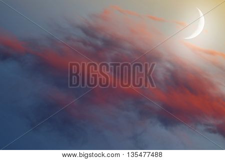 New Moon in clouds with red tint.