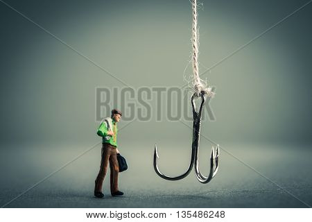 Miniature businessman is staring at fishing needle