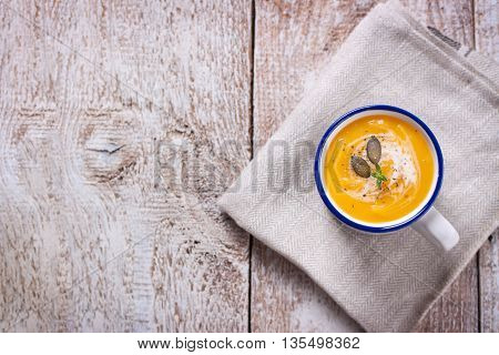 Homemade tasty creamy pumpkin soup puree in a bowl on a wooden background top view