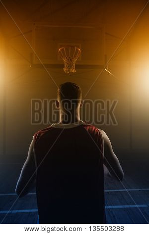 Portrait of basketball player front the back in front of a basket on a gym
