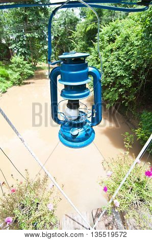 blue lantern hanging in forested and river area