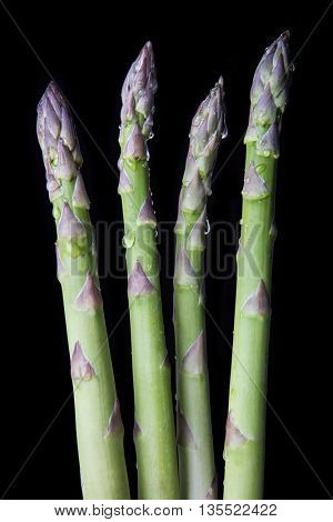 Raw asparagus on black background