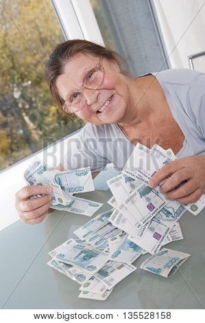 An elderly woman keeps a lot banknotes in denominations of one thousand rubles. Studio photography. Light background.