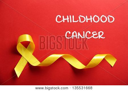 Yellow ribbon and text Childhood Cancer on red background