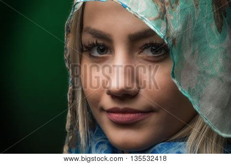 Beautiful young blonde woman against dark green background