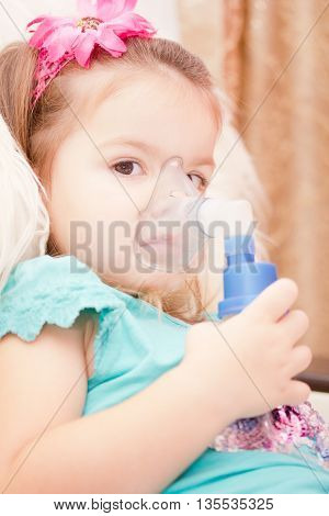 Little girl using an inhaler indoors. nebulizer