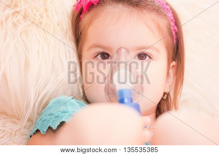 Little girl using an inhaler indoors. nebulizer