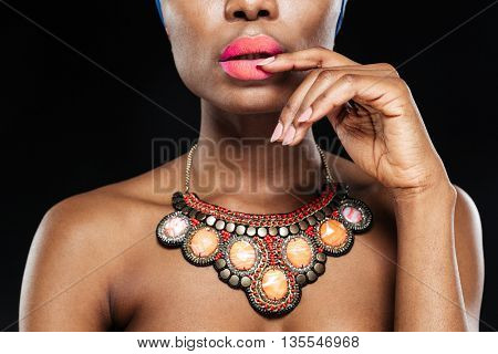 Cropped image of a attractive african woman with her hand on lips isolated on the black background