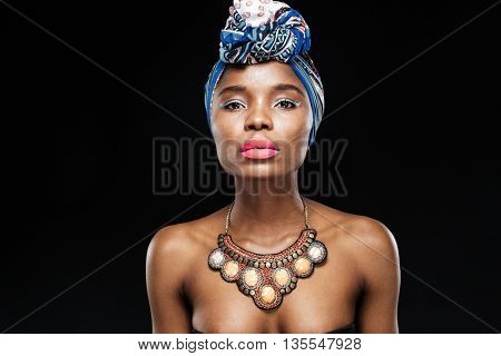 Close-up portrait of a beautiful african woman in shawl on head isolated on the black background