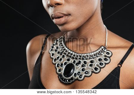 Cropped image of a beautiful african woman wearing necklace isolated on the black background