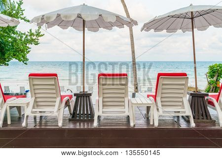 Beautiful beach chairs with umbrella around outdoor swimming pool neary sand and sea