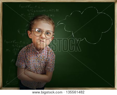 Emotional pupil boy near school chalkboard .